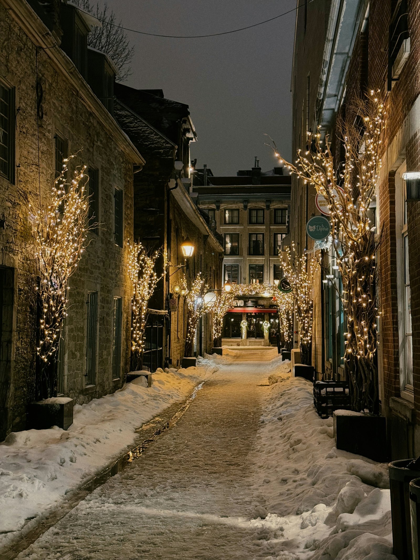 a snowy street lined with buildings and lights